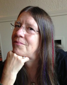 A woman with long hair and glasses looking to her left.