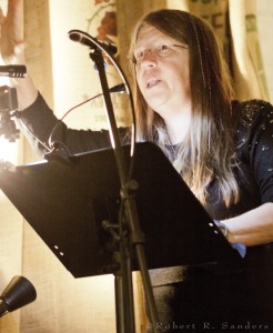 A woman is holding a microphone and reading.