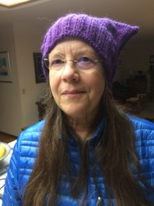A woman wearing purple knitted hat and blue jacket.